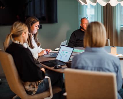 Four persons working in a room with green walls.